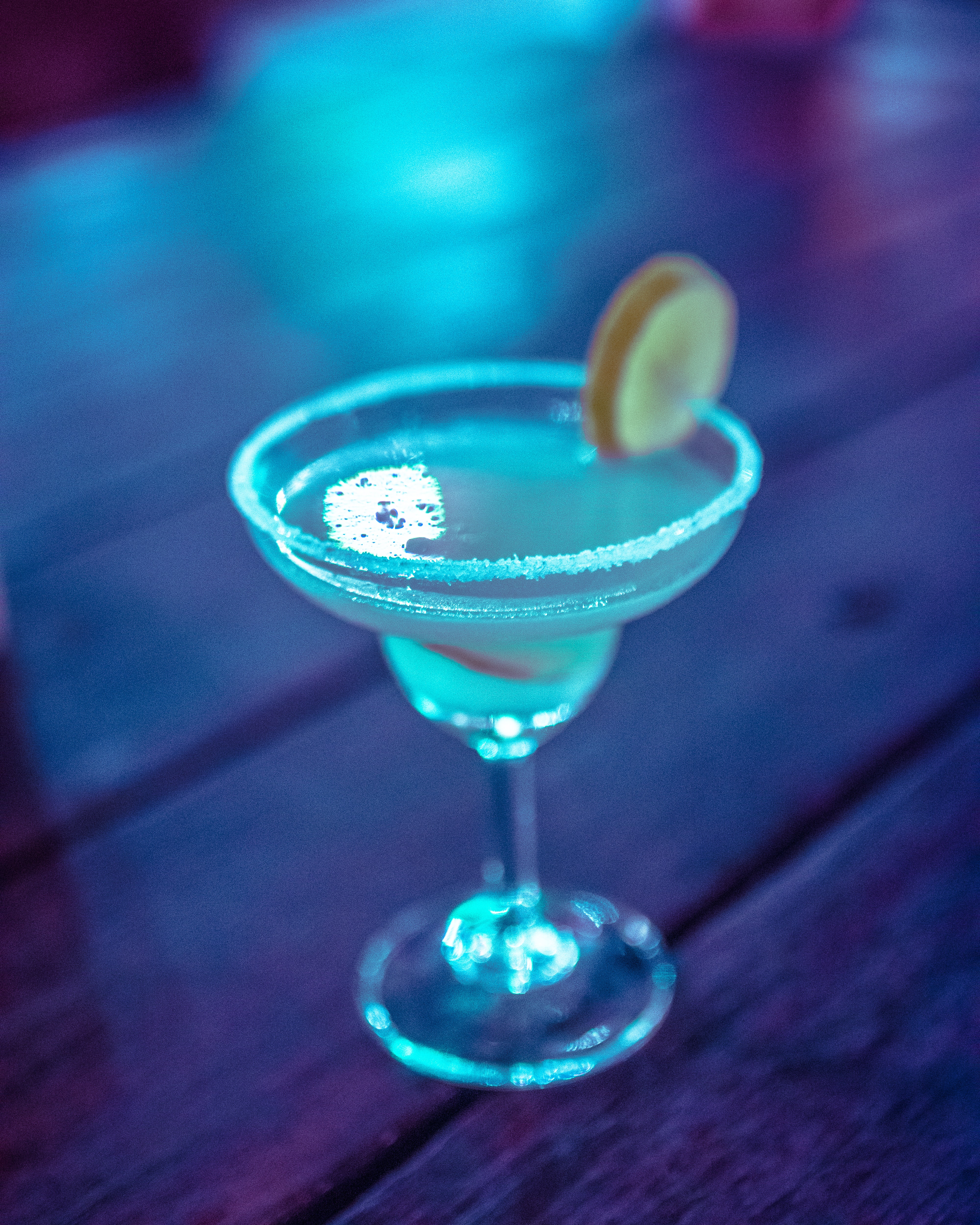 Blended frostbite martini. Blue cocktail in a martini glass, garnished with a lemon wheel.